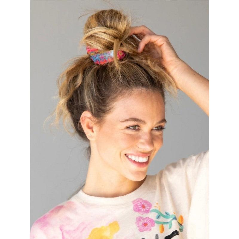 Blonder Messy Bun mit auffälligem pinkfarbenem Haargummi