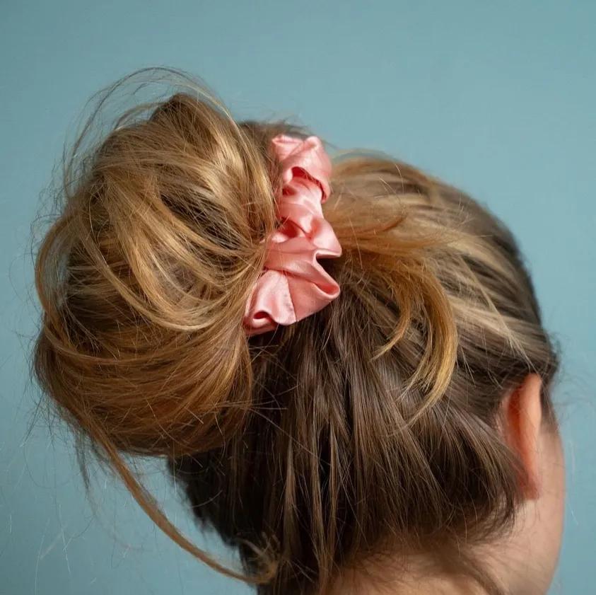 Blonder Messy Bun mit rosafarbenem Scrunchie